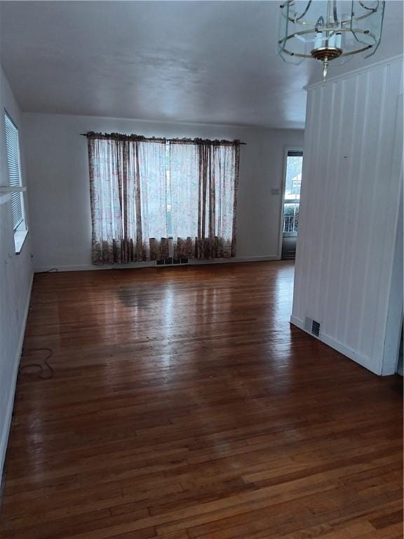 empty room featuring dark hardwood / wood-style flooring and a notable chandelier