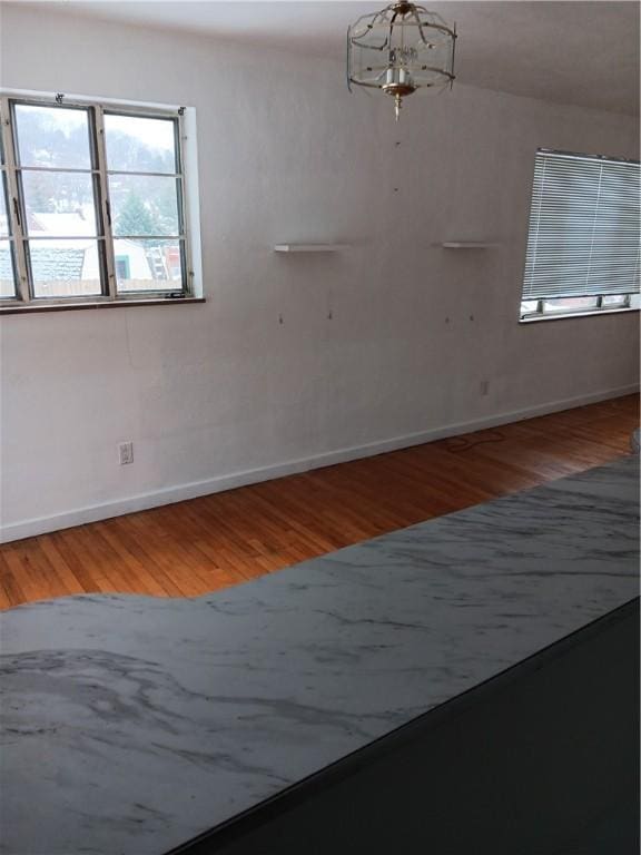 spare room featuring hardwood / wood-style flooring and a chandelier