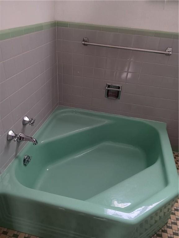 bathroom featuring a washtub, tile patterned flooring, and tile walls