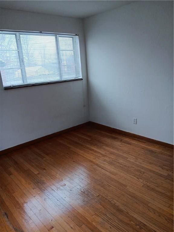 empty room with dark hardwood / wood-style flooring and a healthy amount of sunlight