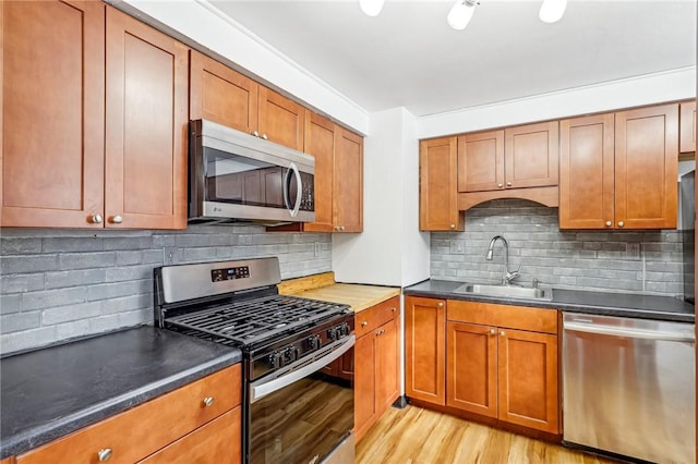 kitchen featuring decorative backsplash, sink, light hardwood / wood-style flooring, and appliances with stainless steel finishes