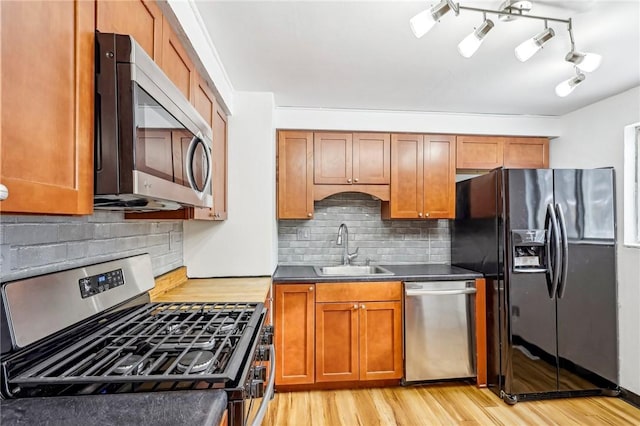 kitchen with backsplash, light wood-type flooring, sink, and appliances with stainless steel finishes