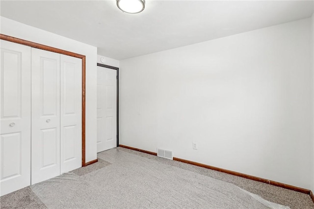 unfurnished bedroom featuring light colored carpet and a closet