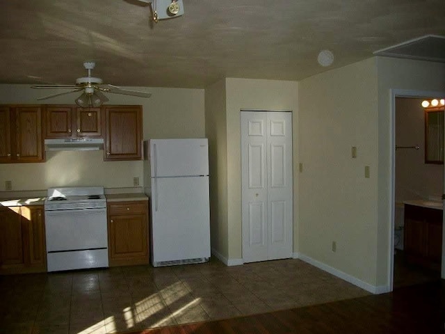 kitchen featuring ceiling fan, dark tile patterned flooring, and white appliances