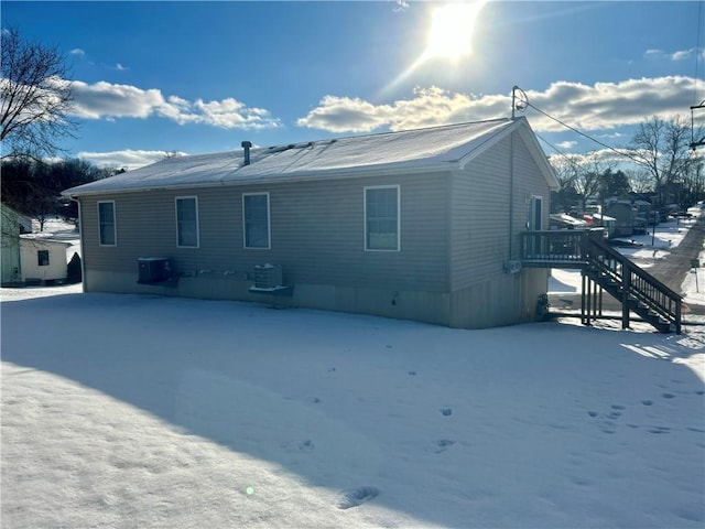 snow covered rear of property with central AC unit