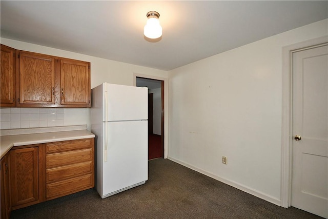 kitchen featuring white refrigerator, dark carpet, and tasteful backsplash