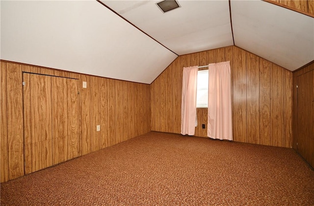 bonus room featuring vaulted ceiling, carpet floors, and wood walls