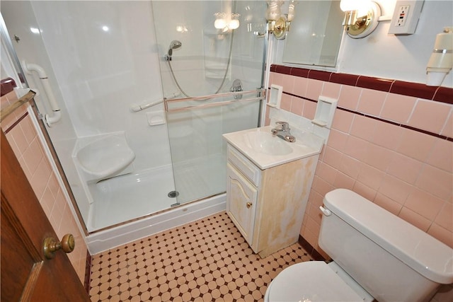 bathroom featuring vanity, toilet, tile walls, and walk in shower