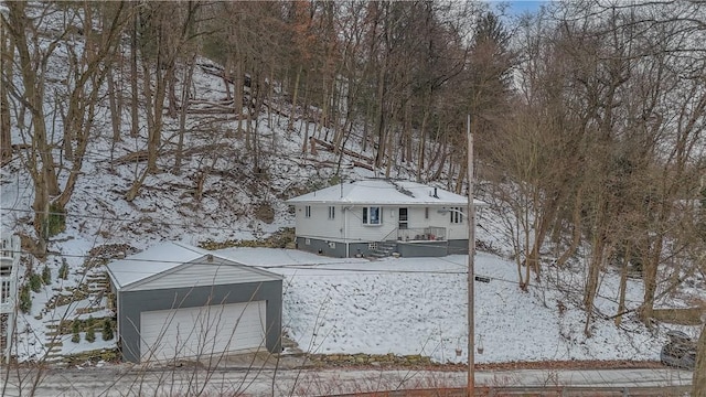 snow covered rear of property with a garage and an outdoor structure