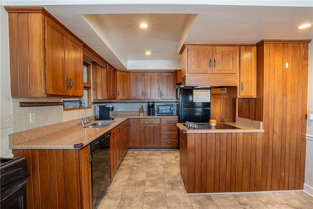 kitchen featuring black appliances, a raised ceiling, sink, decorative backsplash, and light stone counters