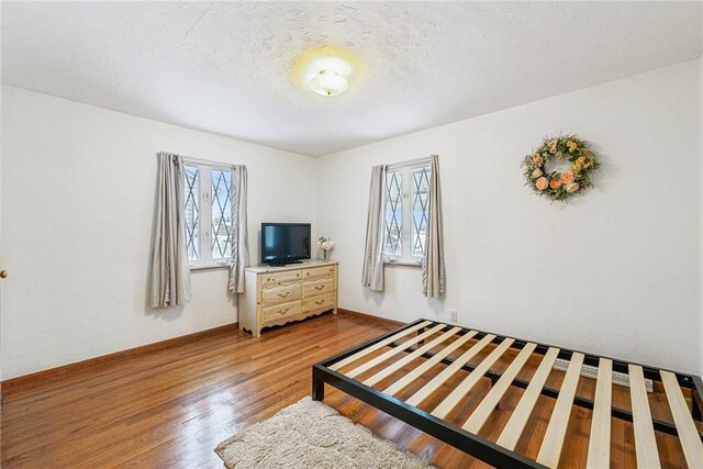 bedroom with hardwood / wood-style flooring and a textured ceiling