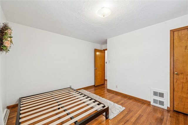 bedroom featuring hardwood / wood-style flooring and a textured ceiling