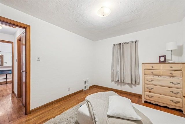 bedroom with light hardwood / wood-style floors and a textured ceiling