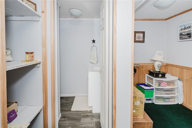 bathroom featuring hardwood / wood-style floors, wood walls, and ornamental molding