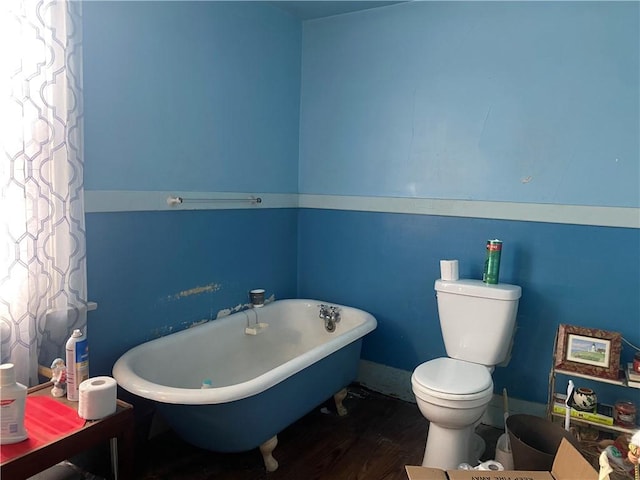 bathroom with hardwood / wood-style floors, a washtub, and toilet