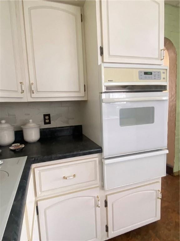 kitchen featuring white cabinets, tasteful backsplash, and oven