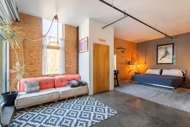 bedroom featuring wood walls and concrete flooring