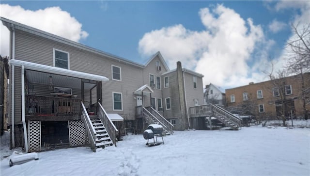 snow covered back of property featuring a wooden deck