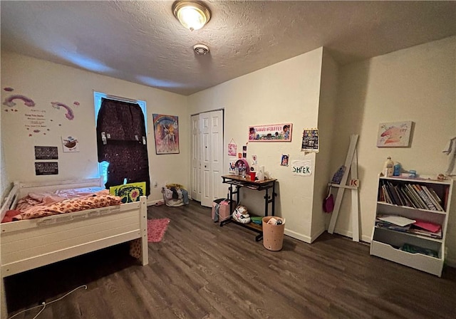 bedroom with a closet, dark wood-type flooring, and a textured ceiling