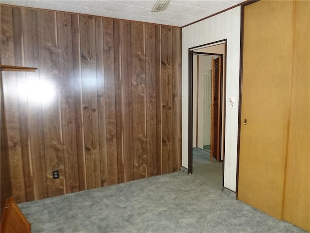 carpeted empty room featuring wooden walls