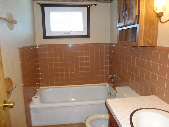 bathroom with a bathing tub, vanity, toilet, and tile walls