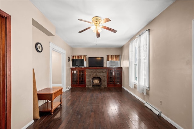 living area featuring a brick fireplace, baseboards, hardwood / wood-style floors, baseboard heating, and a ceiling fan