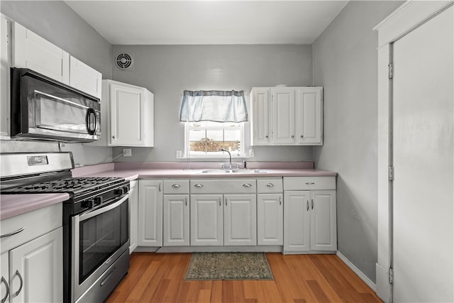 kitchen with visible vents, a sink, stainless steel range with gas cooktop, black microwave, and light countertops