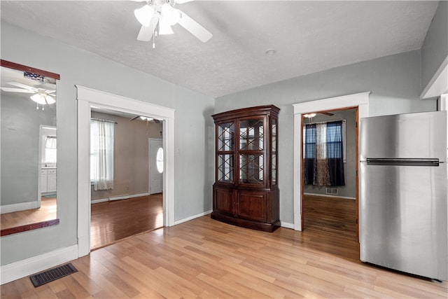 foyer with baseboards, visible vents, a ceiling fan, and light wood-style floors