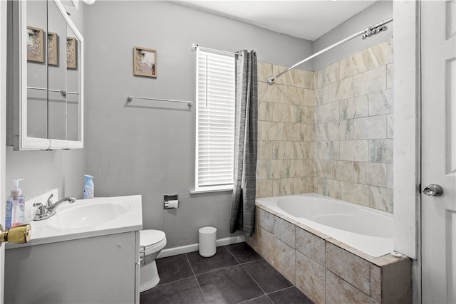 bathroom featuring tile patterned floors, tiled shower / bath, toilet, baseboards, and vanity