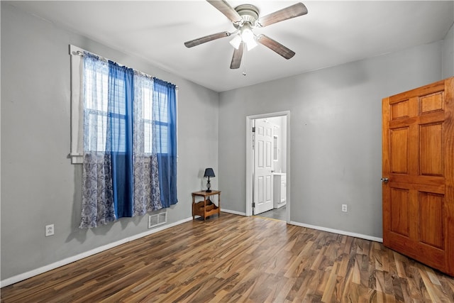 interior space featuring ceiling fan, visible vents, baseboards, and wood finished floors