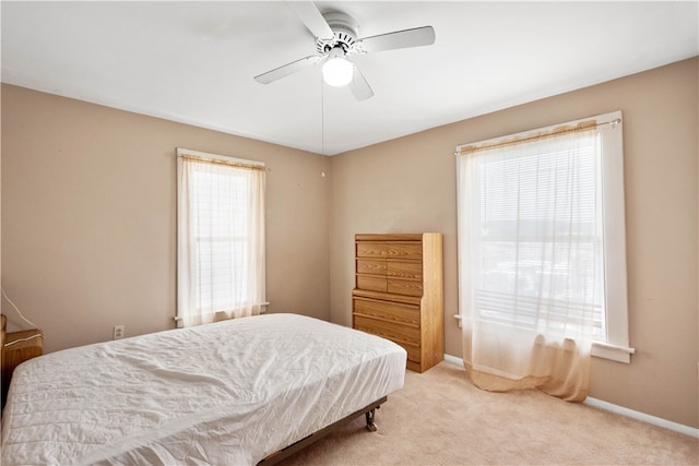 carpeted bedroom featuring multiple windows, baseboards, and ceiling fan