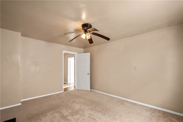 carpeted empty room featuring a ceiling fan and baseboards