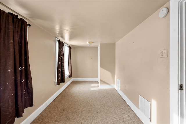 unfurnished room with carpet, visible vents, and baseboards