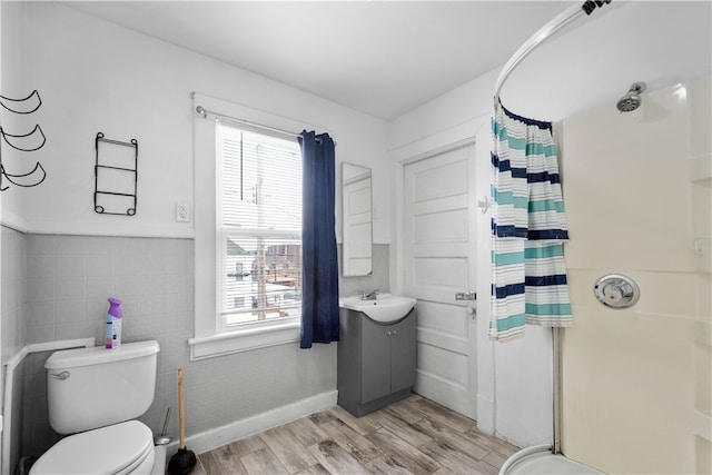 full bathroom featuring tile walls, toilet, a stall shower, wood finished floors, and vanity