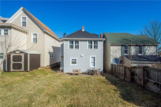 rear view of house with a storage unit, an outbuilding, a lawn, a patio, and fence