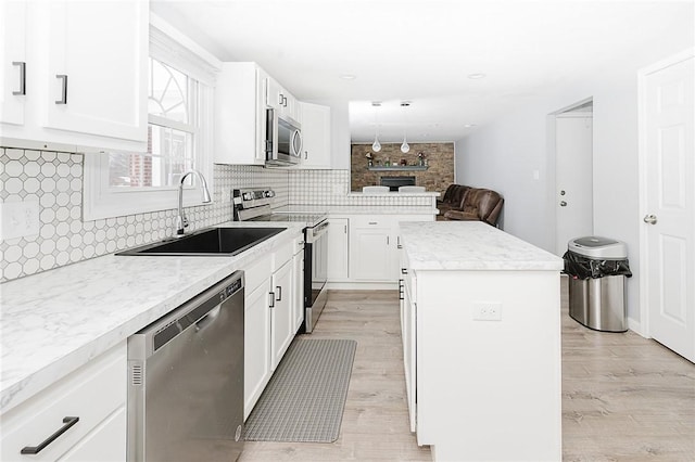 kitchen featuring white cabinets, sink, a center island, and appliances with stainless steel finishes