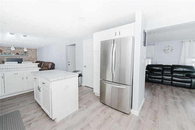 kitchen featuring stainless steel refrigerator, white cabinetry, a kitchen island, and light hardwood / wood-style floors