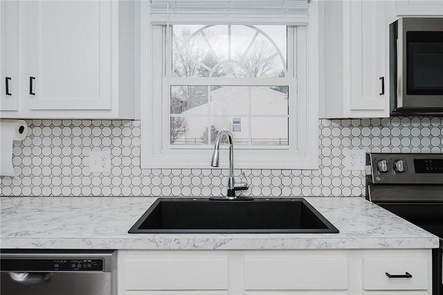 kitchen featuring backsplash, white cabinetry, sink, and stainless steel appliances