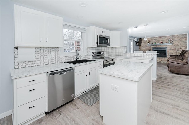 kitchen with sink, white cabinetry, hanging light fixtures, and appliances with stainless steel finishes