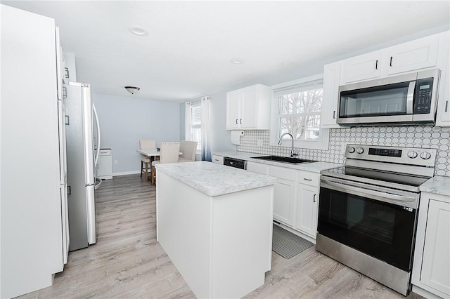 kitchen featuring a center island, white cabinets, sink, light wood-type flooring, and stainless steel appliances