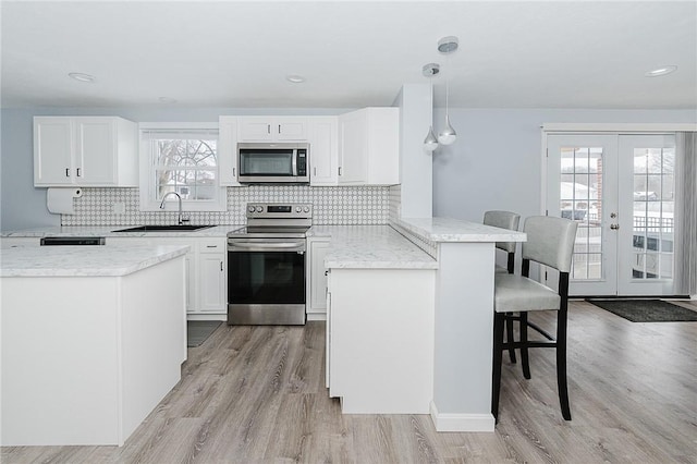 kitchen with sink, hanging light fixtures, a kitchen breakfast bar, kitchen peninsula, and appliances with stainless steel finishes