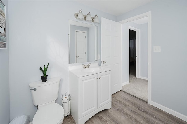 bathroom with hardwood / wood-style floors, vanity, and toilet