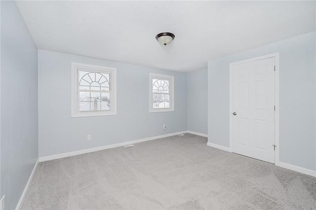 unfurnished room with light colored carpet and a textured ceiling