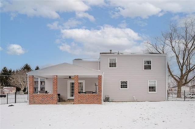 snow covered rear of property featuring ceiling fan and a porch