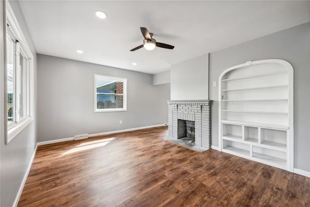 unfurnished living room with a fireplace, wood-type flooring, plenty of natural light, and ceiling fan