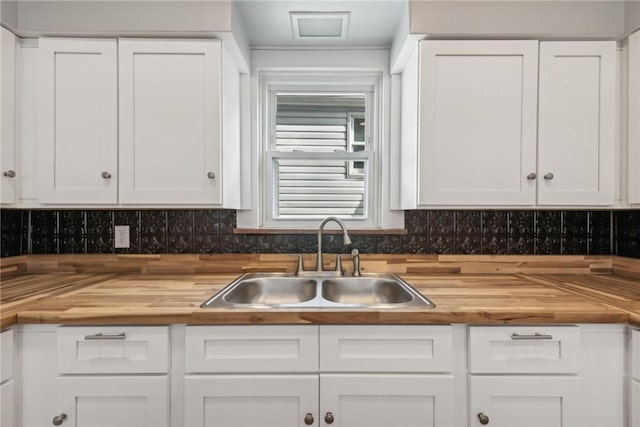 kitchen featuring white cabinets, butcher block counters, sink, and tasteful backsplash