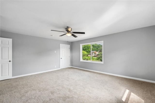 unfurnished room with ceiling fan and carpet