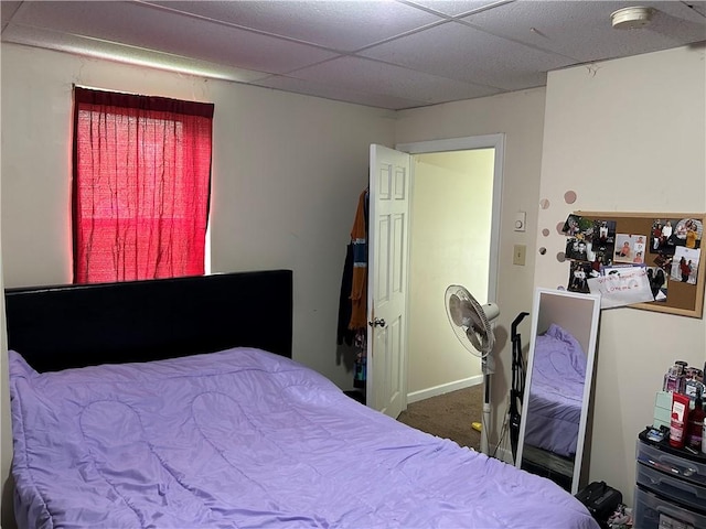 carpeted bedroom featuring a drop ceiling