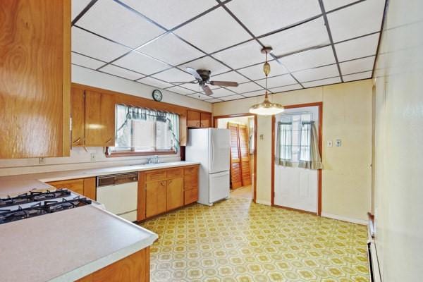 kitchen with white appliances, decorative light fixtures, plenty of natural light, and a drop ceiling