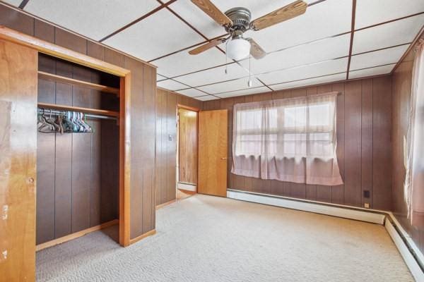 unfurnished bedroom with ceiling fan, light carpet, a baseboard radiator, and a closet